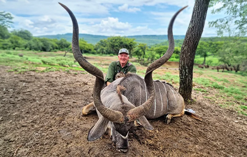 Hunter with large trophy kudu bull in South African bushveld at Aloe Africa Hunting Safaris