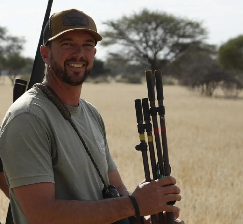Jurgens "Yogi" Potgieter, Professional Hunter with Aloe Africa Hunting Safaris, holding shooting sticks on the South African plains.