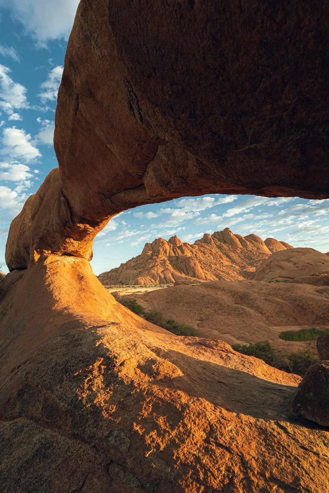 Arco de roca natural que enmarca montañas desérticas bajo un cielo azul en Namibia