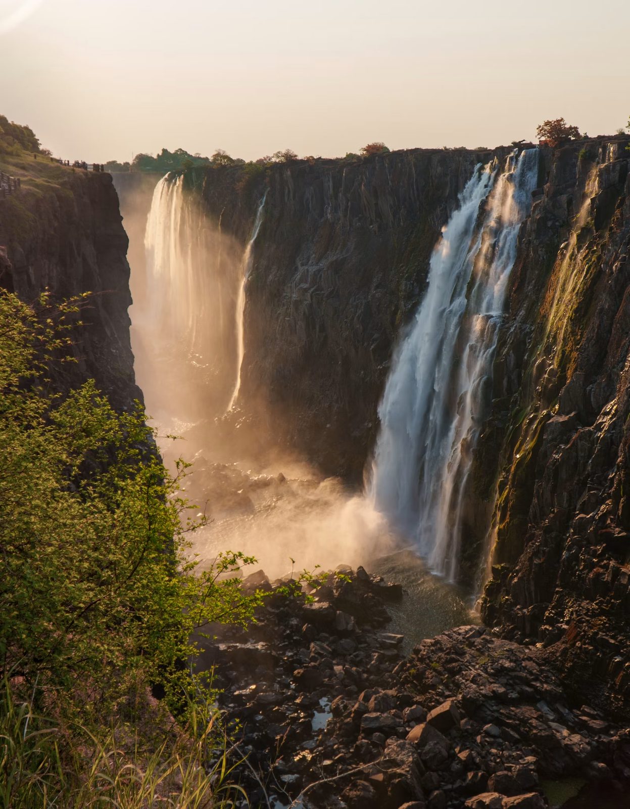 Puissantes chutes Victoria tombant en cascade sur des falaises rocheuses au coucher du soleil, Zimbabwe